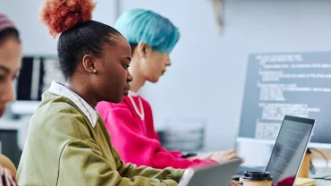 Pessoas concentradas em computadores em um ambiente de escritório.