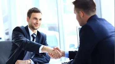 Dois homens de terno se cumprimentando em um escritório moderno.