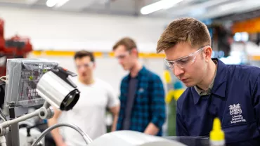 Homem de óculos de proteção trabalha em laboratório de engenharia.