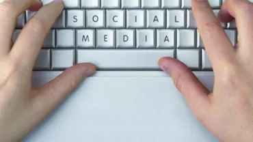 Mãos digitando 'social media' em um teclado.