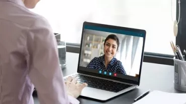 Mulher em videochamada olhando para um laptop.