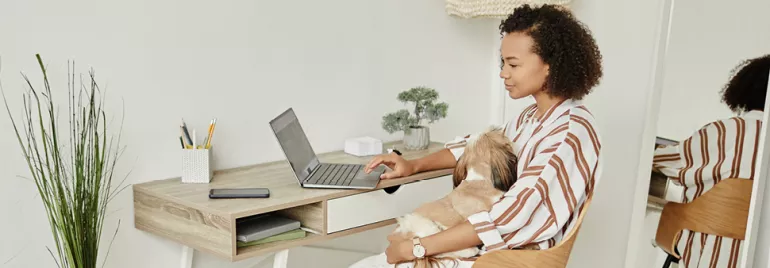 Mulher a usufruir de opções de trabalho flexível ao trabalhar remotamente a partir do seu escritório arrumado em casa, a utilizar um portátil.